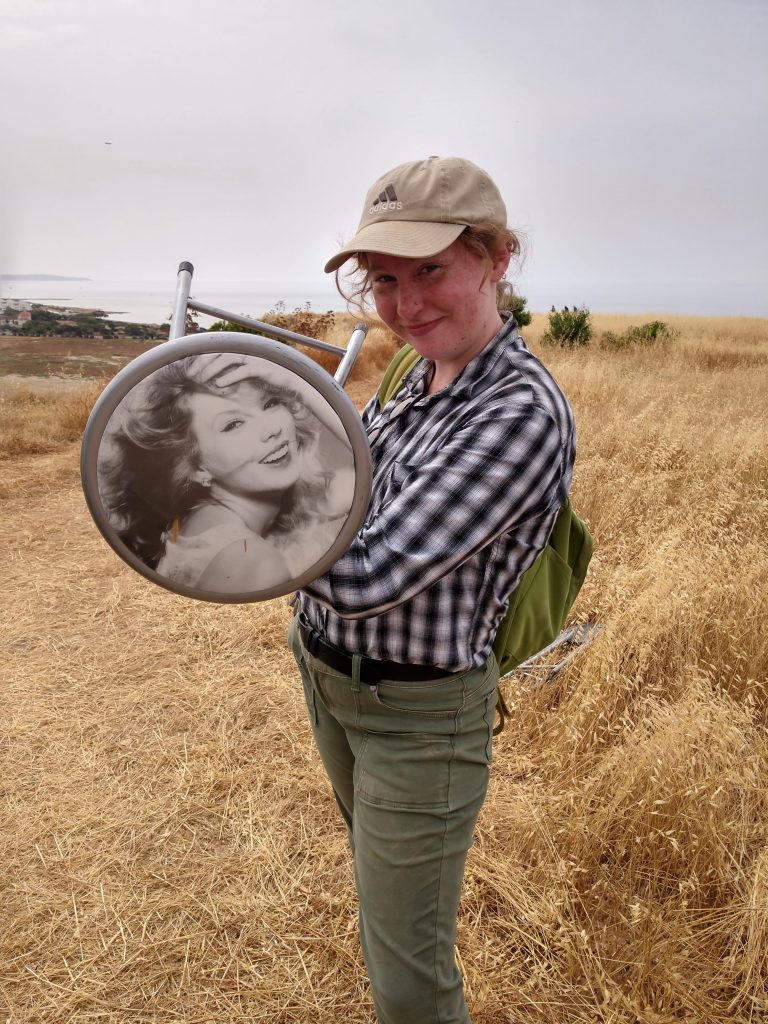 A woman holds a cheap-looking stool with a picture of Taylor Swift on the cushion