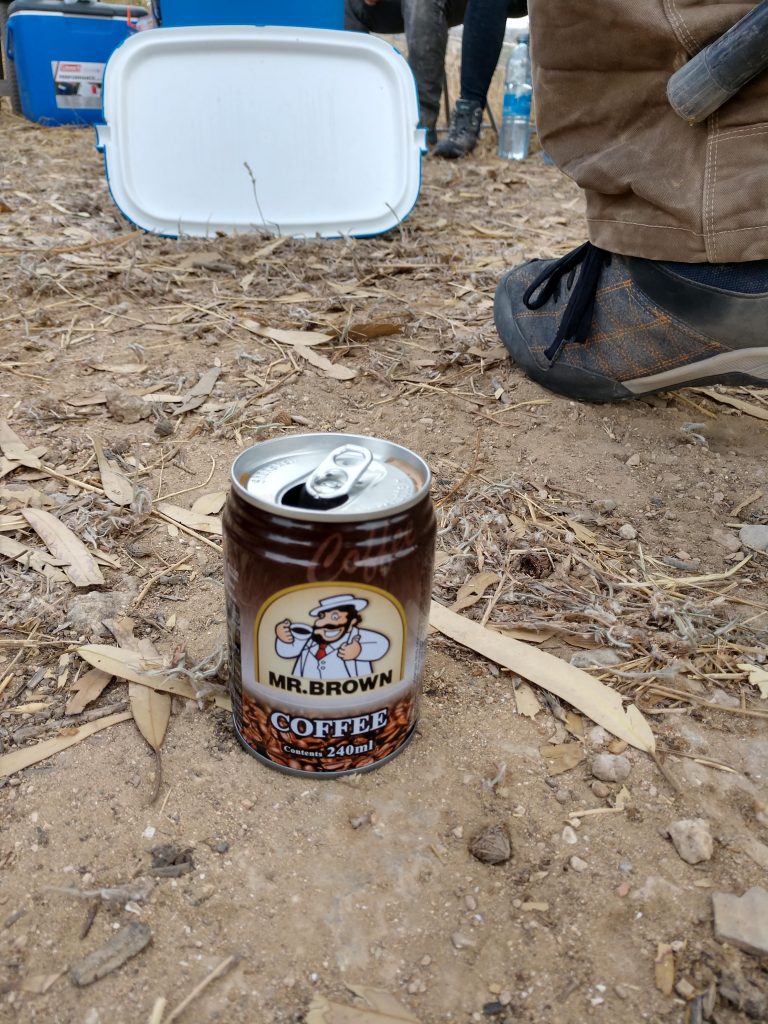 A can sitting on the dirty ground reads "Mr. Brown Coffee"