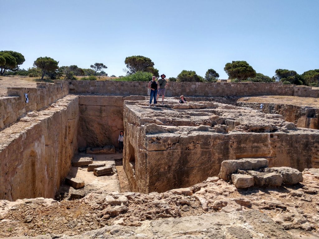 A few people stand on top of ancient rock-cut tombs