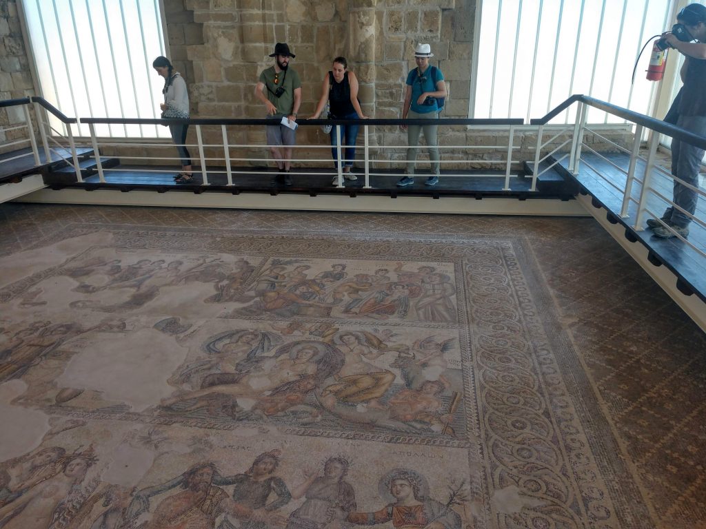 A group looks at ancient multicolored mosaics from a raised walkway