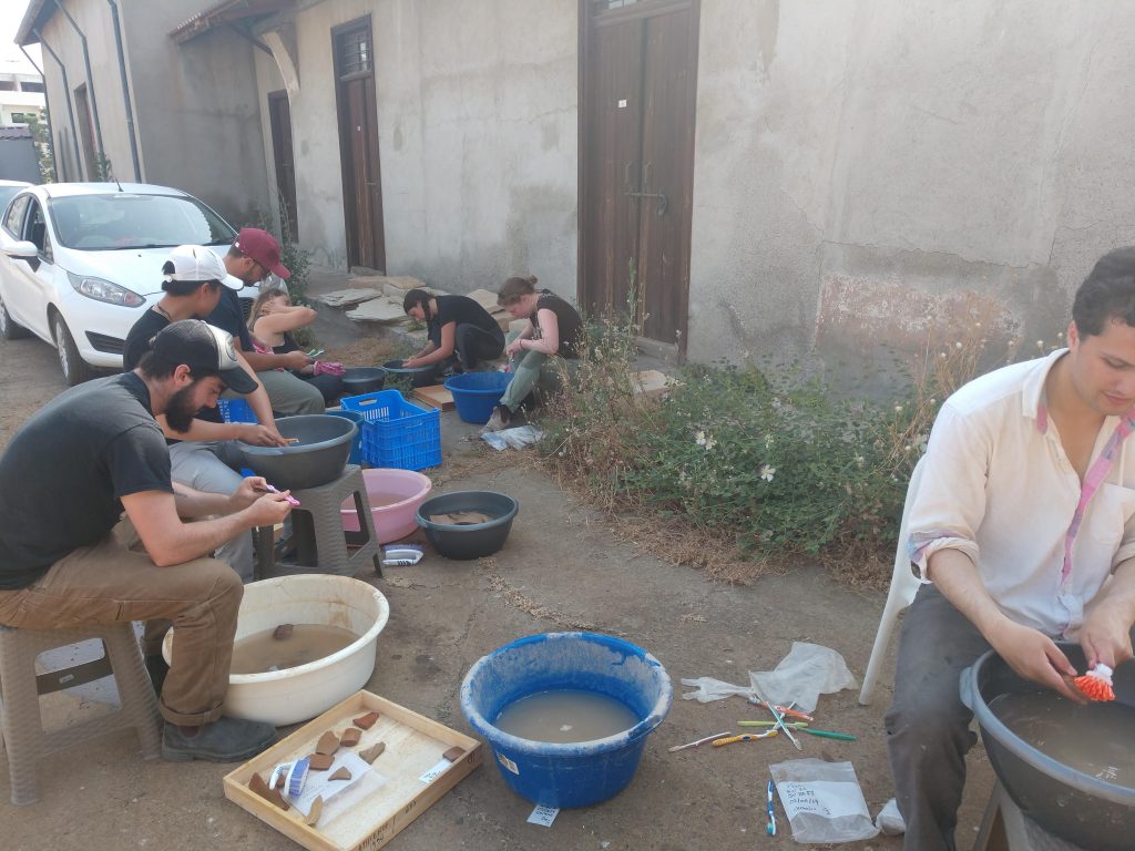 A group washes pottery outside in large basins