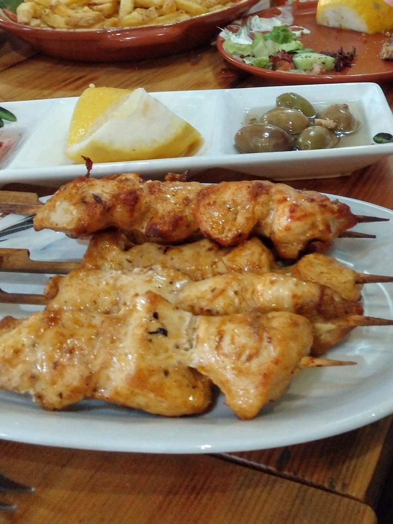 marinated chicken pieces on a skewer sit on a table among other small plates