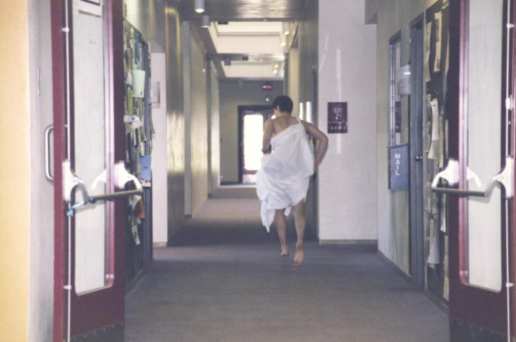 A student dressed in a toga running down a hallway. 