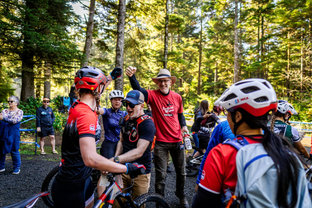 Duncan Parks, class of 1992 pictured center, fist bumps a member of the Portland Metro Composite youth mountain bike team. Duncan volunteers as a team director and level 3 coach. 